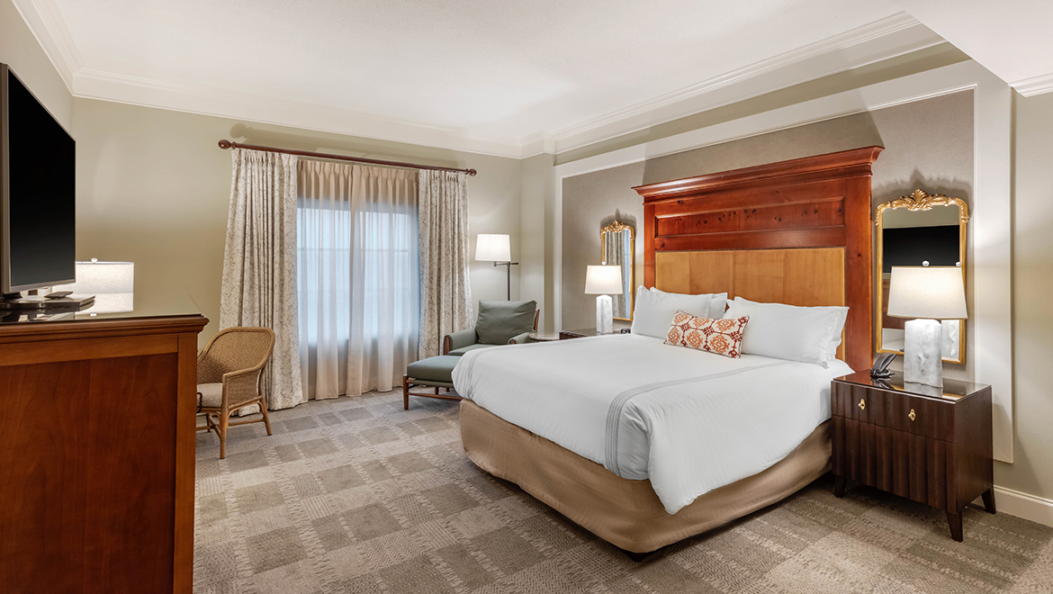A Deluxe King room featuring a king-size bed, activity desk and lounge chair.
