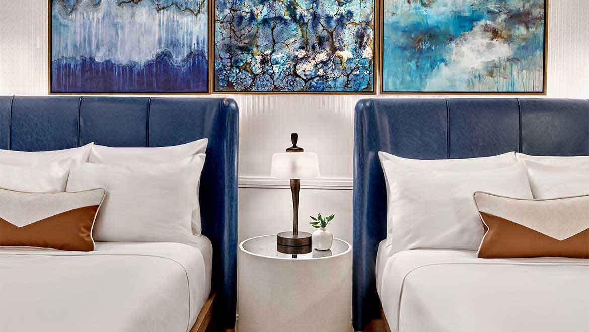 Two beds with nightstand between them.