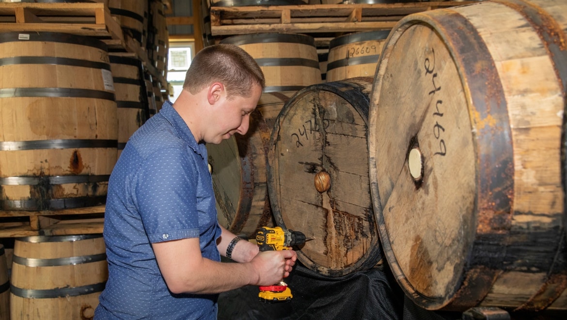 Man removing bourbon from barrel.