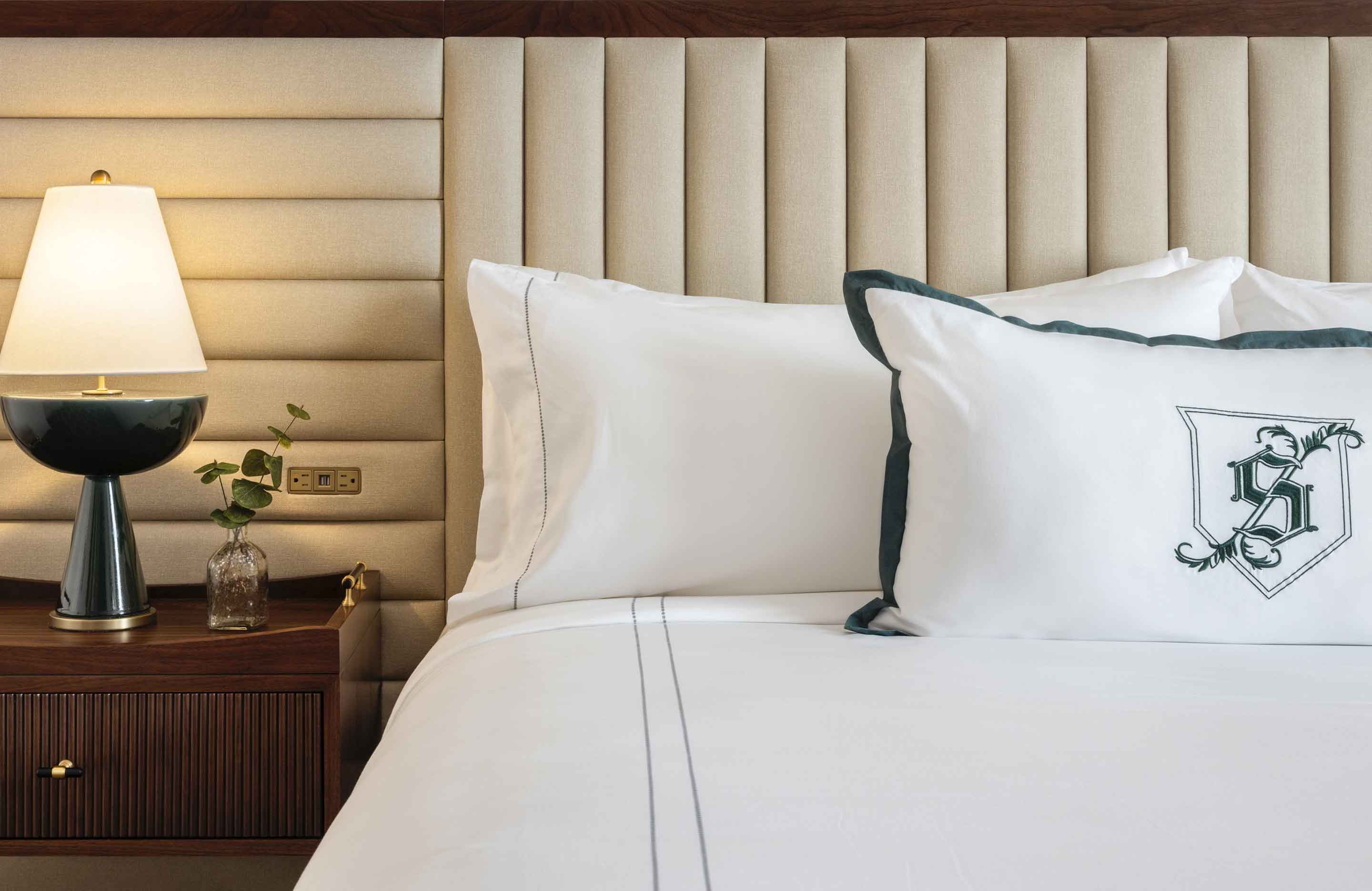 Bed with pillows and lamp on nightstand.