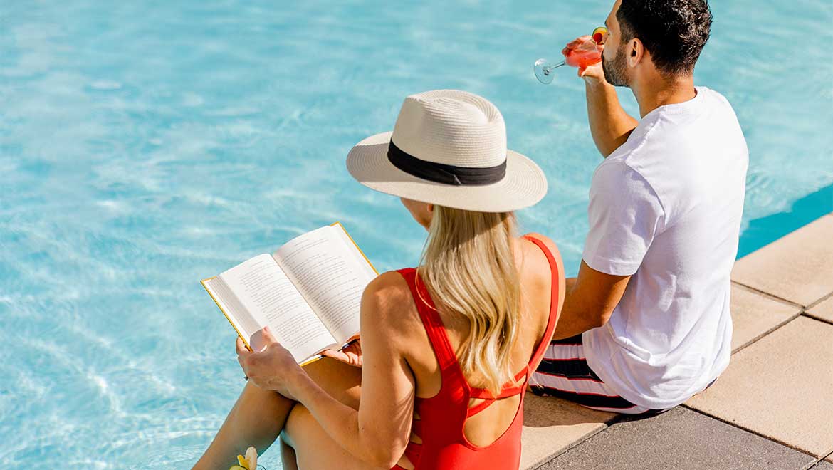 Woman reading a book by the pool